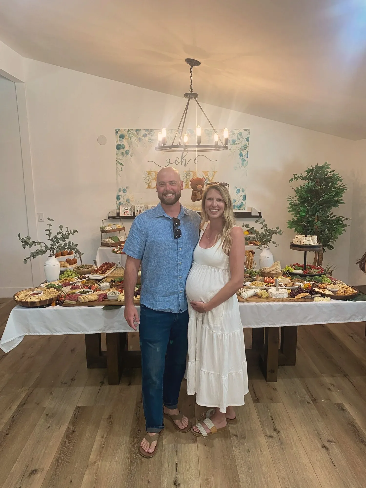 Kim and Cameron standing together in front of the grazing table, Kim in a white dress