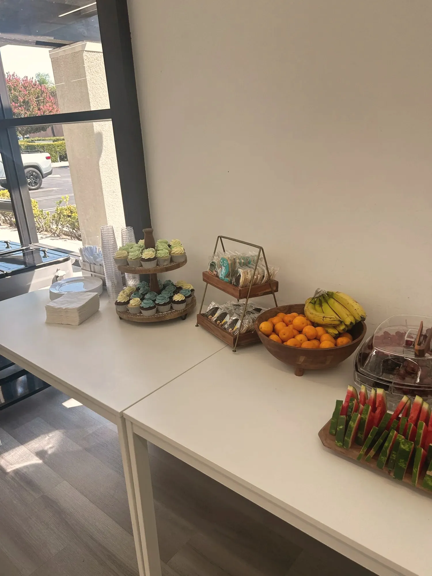 A dessert table with green and turquoise frosted cupcakes, themed cookies, and bowls of fresh fruit