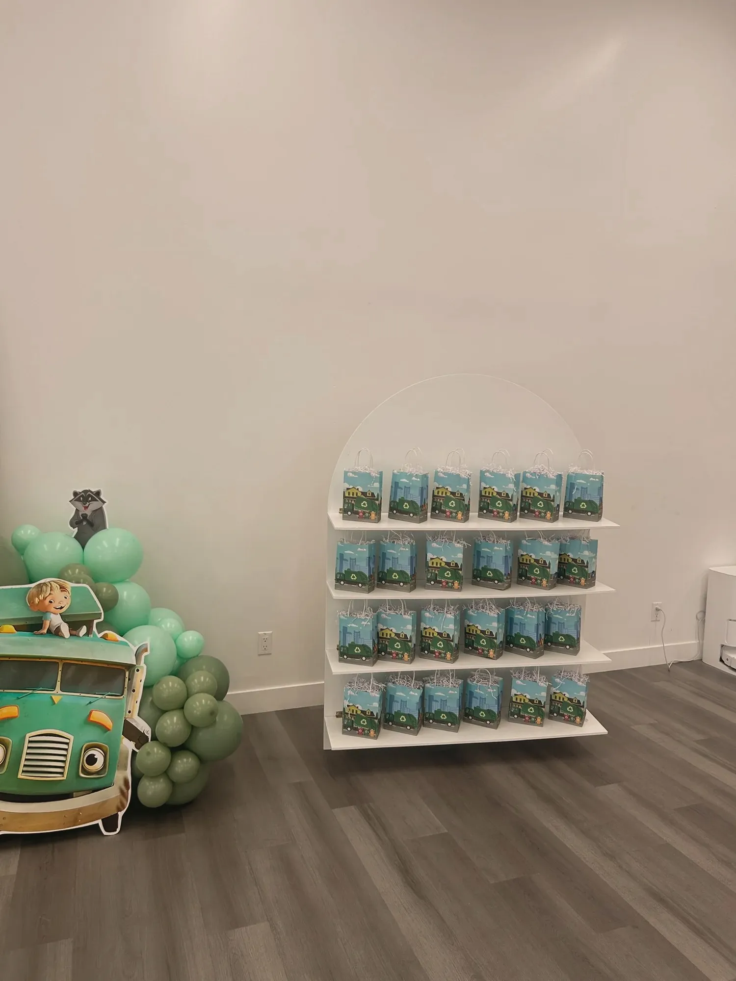 An arched white shelf lined with matching trash-truck party favor bags for the guests, beside the truck cutout
