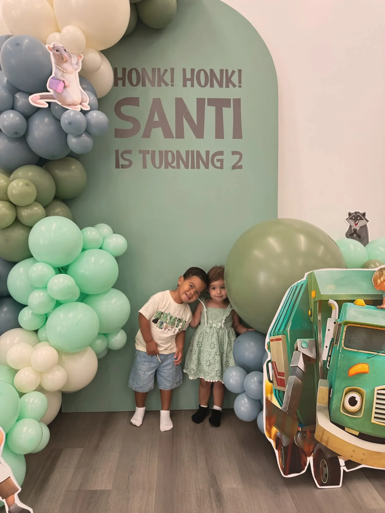 Santi and a friend leaning together in front of the birthday backdrop