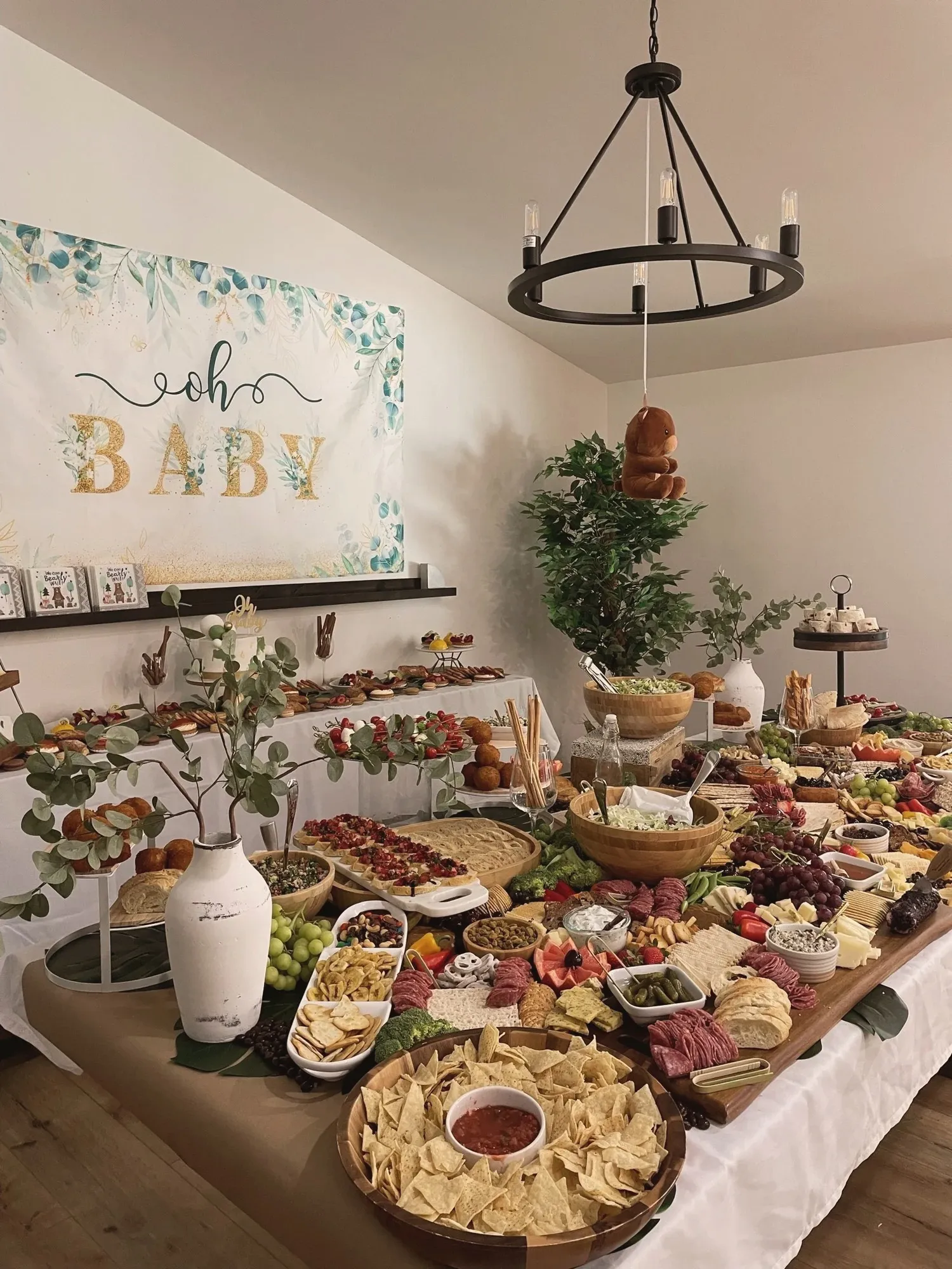 The grazing table seen down its length, layered with cured meats, cheeses, grapes, breads, and dips on long wood boards